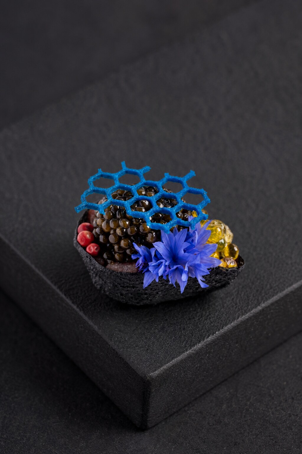 Caviar canapé with a blue honeycomb garnish on deep charcoal stone